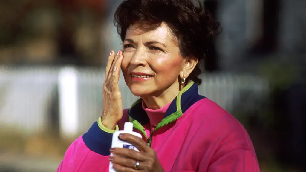 A woman applying sunscreen to her face