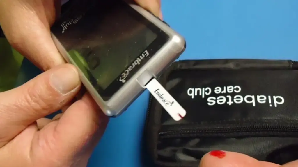 A person using a blood glucose meter and test strip