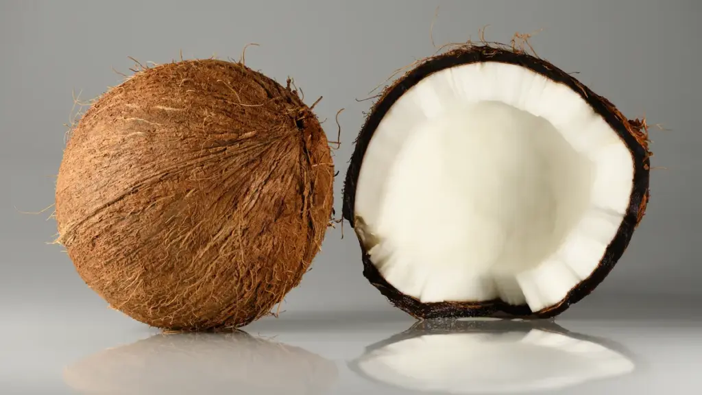 Whole coconuts beside one cracked open to show the flesh