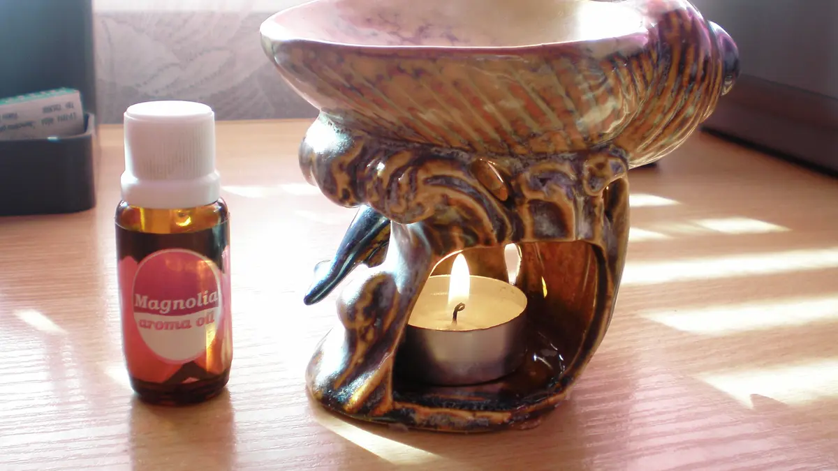 A candle-heated aroma lamp beside a small fragrance-oil bottle