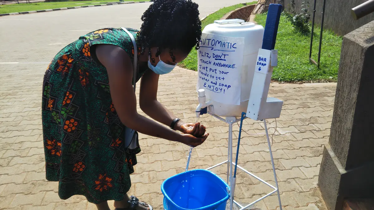 A person washing their hands at a touchless soap and water station