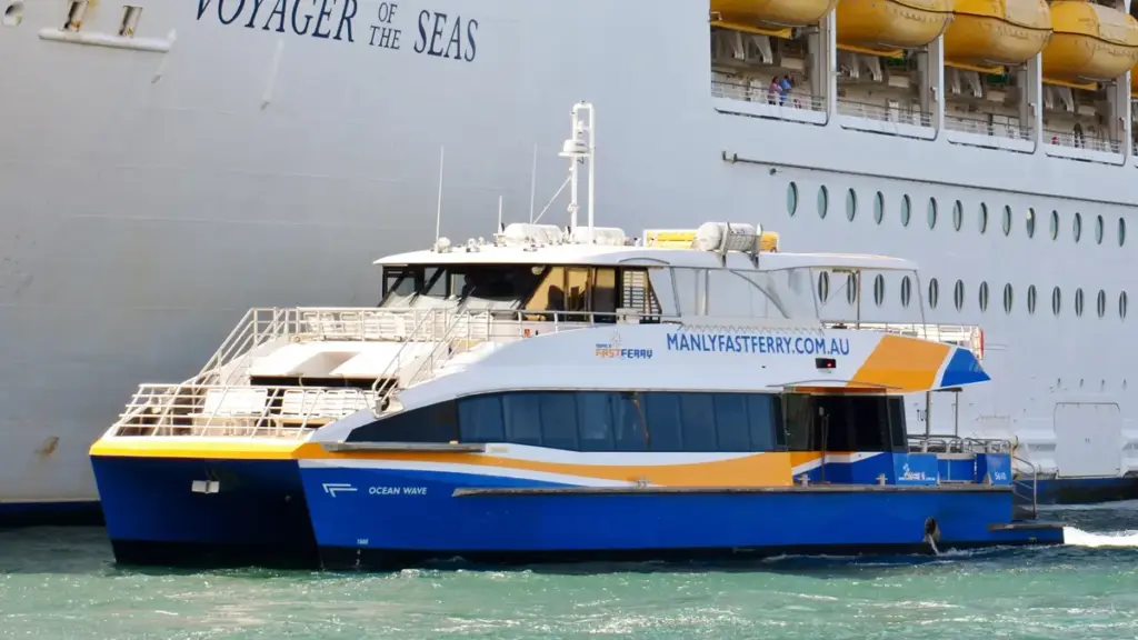 A passenger ferry travelling beside a larger ship on Sydney Harbour