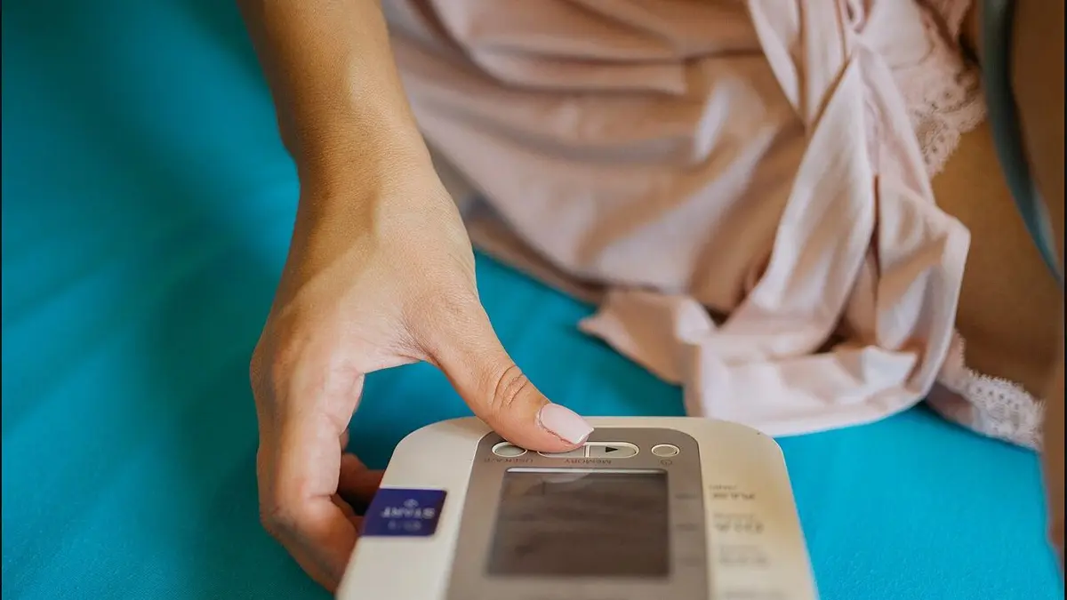 Woman holding a digital blood-pressure monitor; this is not a blood-glucose meter