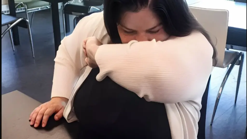 Woman coughing into her elbow; this photo does not diagnose bronchitis