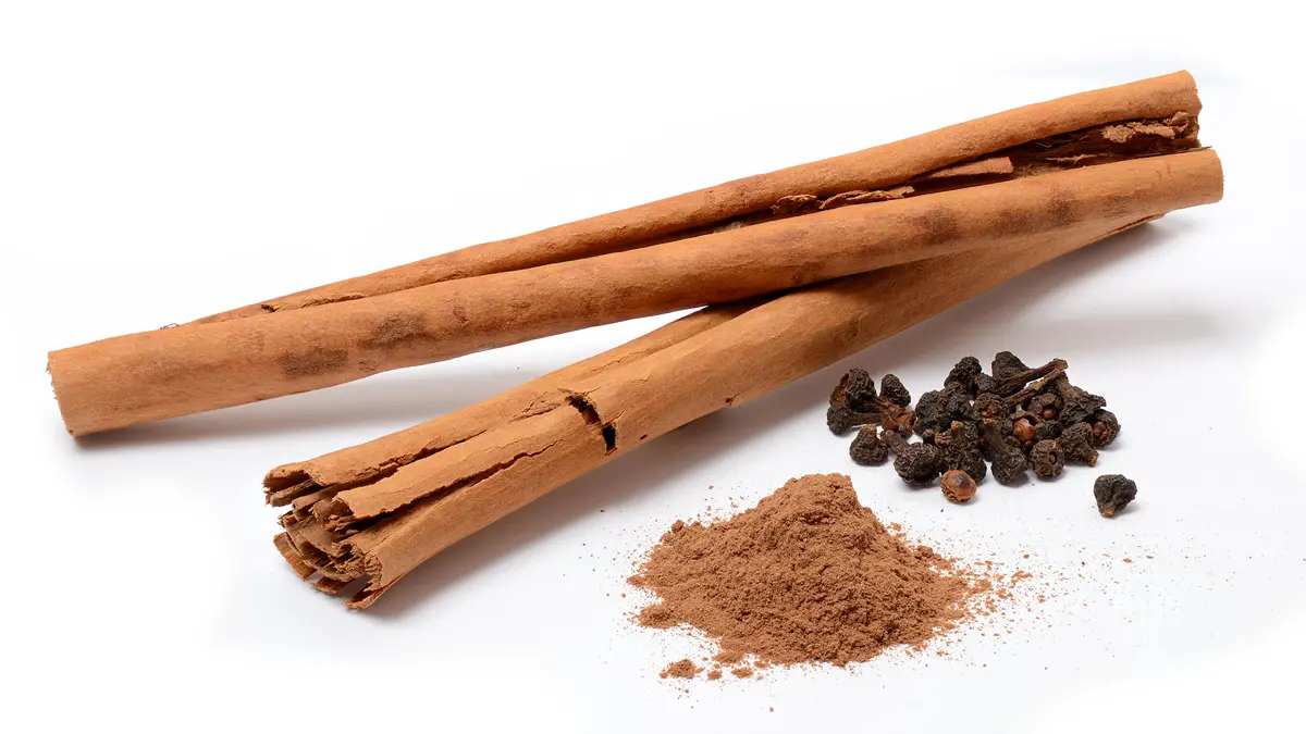 Cinnamon bark sticks beside ground cinnamon and peppercorns