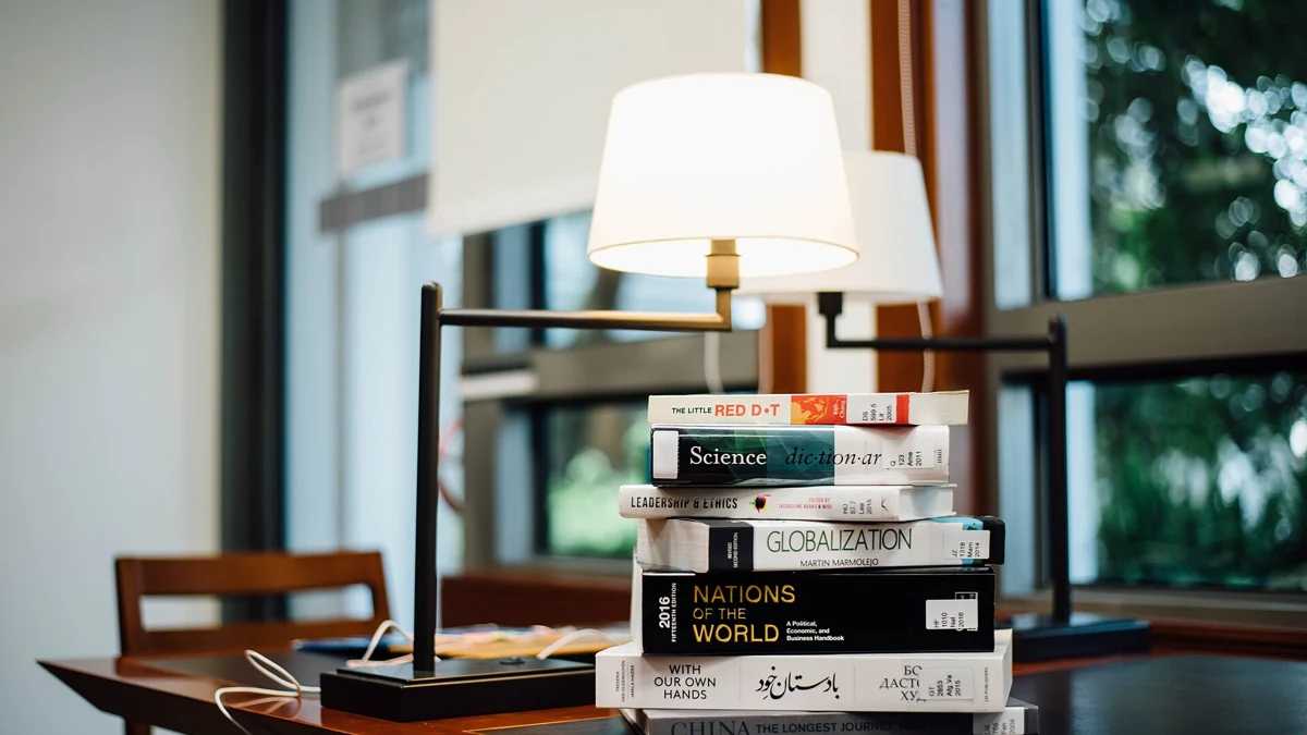 A stack of books beside a reading lamp